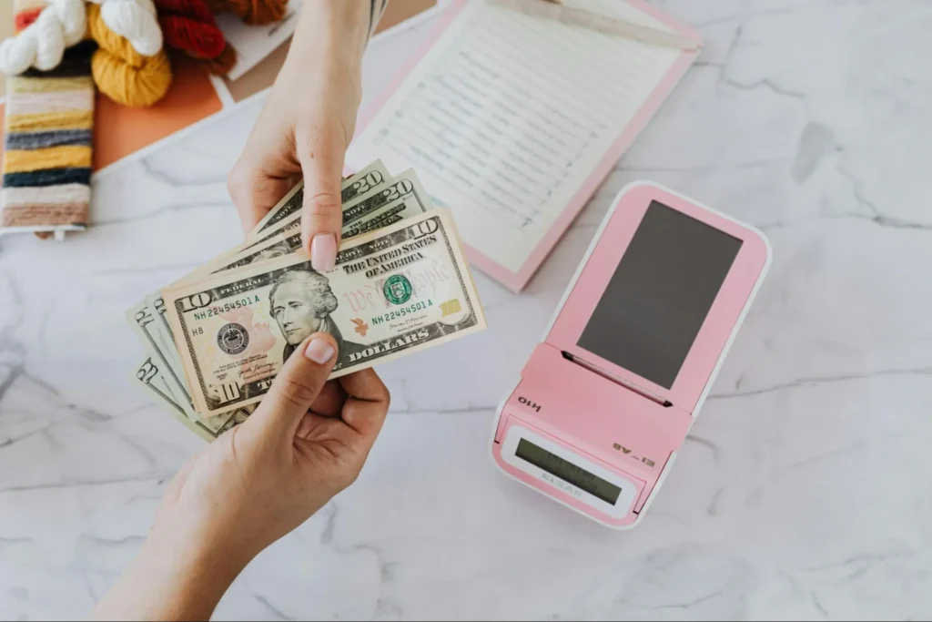 Dollars and a card payment terminal, symbolizing the payment settlement process and its complexities.
