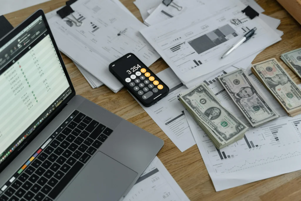 A business owner’s laptop and sales money, helping them calculate their cash flow needs.