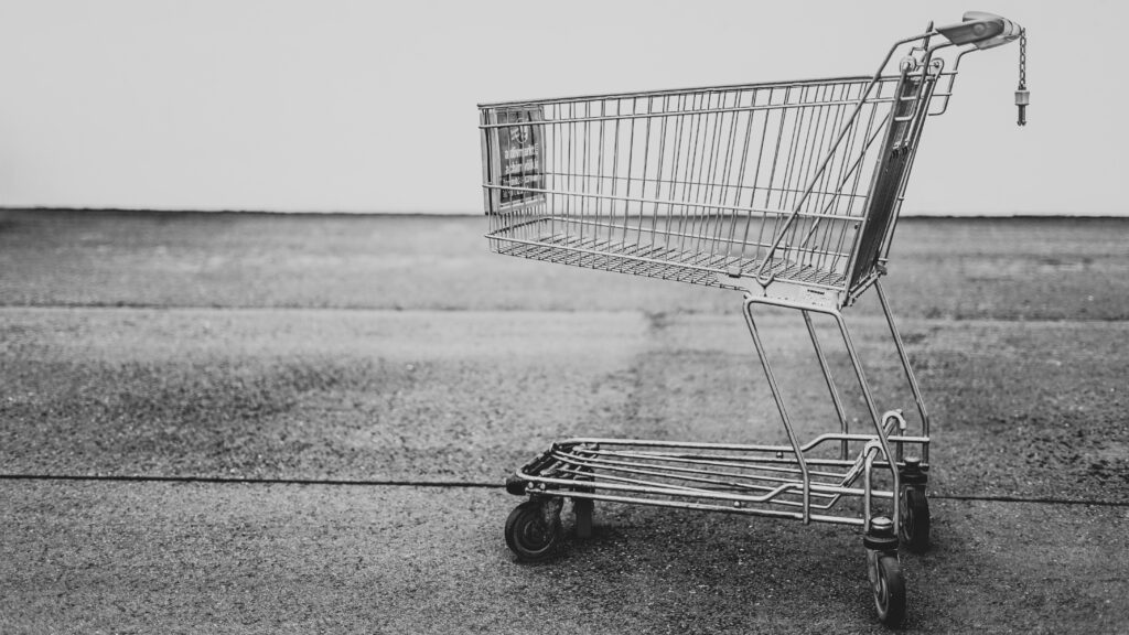 Grey metal shopping cart standing alone on a grey background